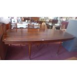A 1970's rosewood dining table raised on tapered legs and brass feet.