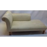 A contemporary chaise lounge with cream suede upholstery and raised on mahogany legs