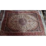 A Keshan style rug with central floral medallion on a beige ground contained by borders.