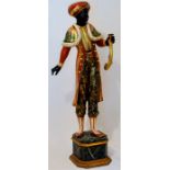 Reproduction Blackamoor figure, standing on a faux marble and gilded base and elaborately and bright