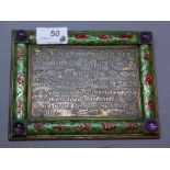 A brass German plaque decorated with green and red enamel and amethyst glass cabouchons with