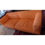 A contemporary three seater sofa having orange Alcantara removable covers and raised on steel legs.