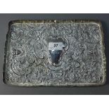 A silver tray decorated with floral and foliage and faces depicting emotions.