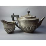 A silver tea pot and milk jug (finale loose), marked London 1886/7, Edward Hutton. Approx.675g.
