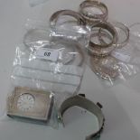 A collection of silver bangles to include a small silver mounted clock and bracelet with semi