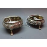 Two Victorian silver salts, London 1842 and 1877, repousse embossed design, raised on three feet,