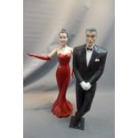 Two fibre glass model of a lady in a red dress and a man in a tuxedo,