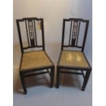 A pair of dining chairs with rattan seats.