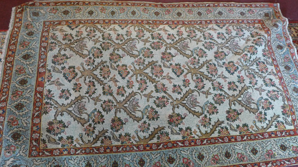 A Qum rug, traditional floral & bird design over cream ground, within pale blue & red borders.