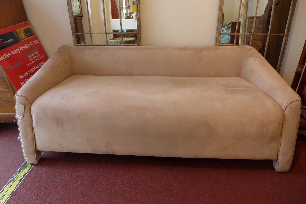 A contemporary Art Deco style three seater sofa with beige alcantara upholstery.