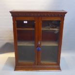 A late 19th Century oak wall hanging display cabinet with two glazed doors enclosing adjustable