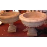 A pair of reconstituted stone urns decorated with classical swags.