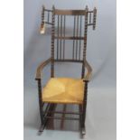 An Ernest Gimson black stained ash and beech rocking chair, with bobbin turned wings and finials,