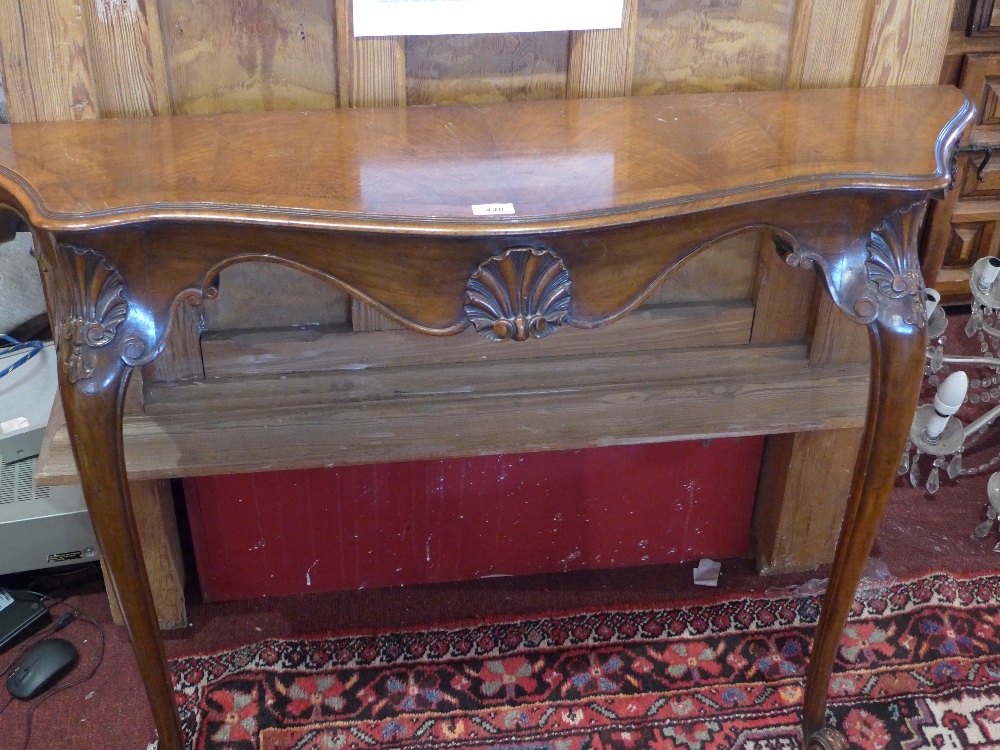 An early 20th Century walnut console table with carved shell decoration.