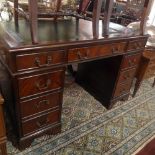 A 20th Century mahogany pedestal desk with an arrangement of nine drawers and raised on carved