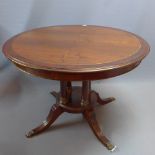 A Regency style mahogany dining table having four column supports and paw feet with additional leaf.