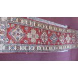 A red ground Kazak runner, geometric designed medallions to centre,