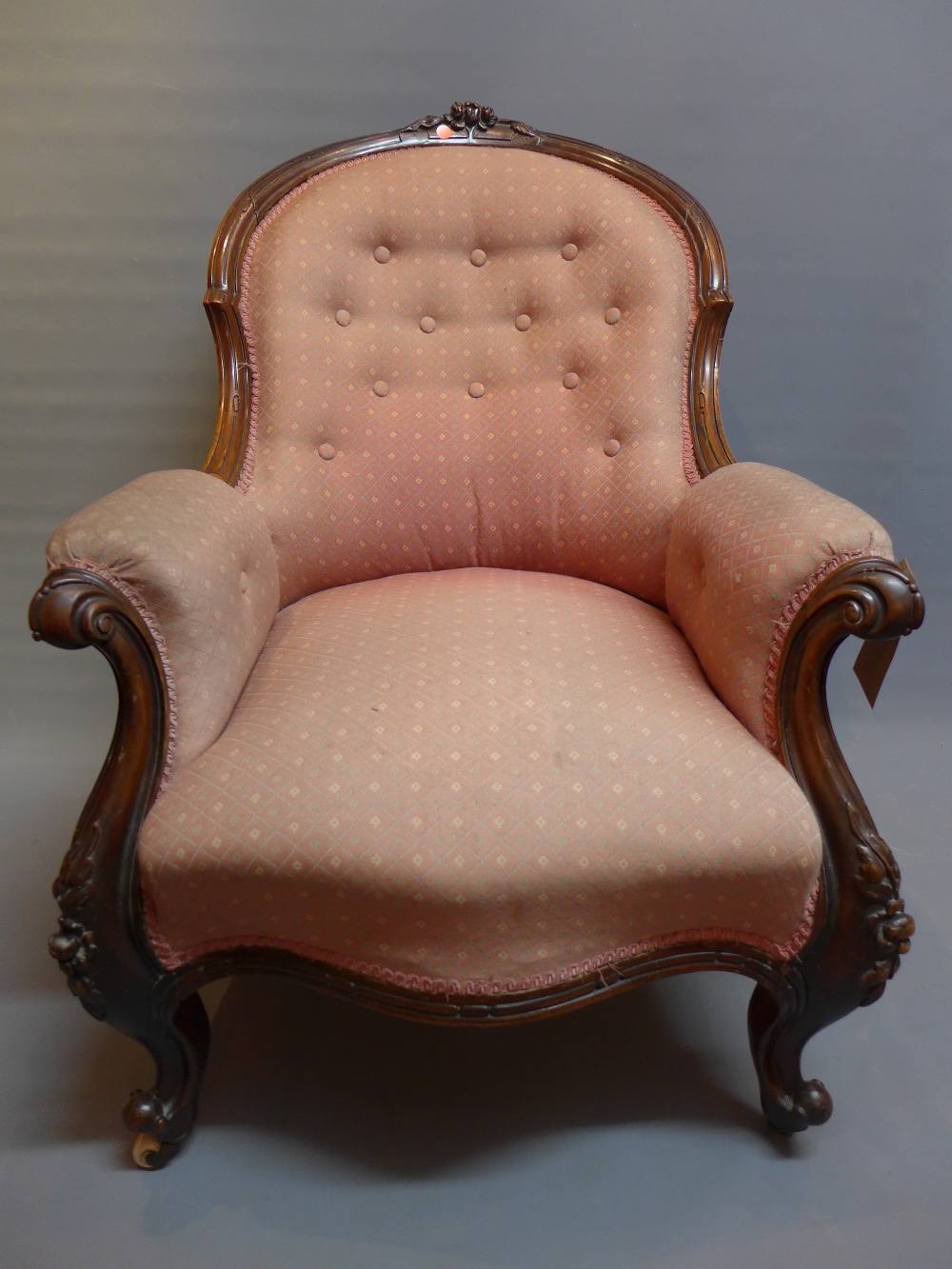 A Victorian rosewood spoon back armchair with button back upholstery raised on carved cabriole legs