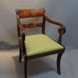 A regency mahogany scroll arm chair raised on sabre legs.