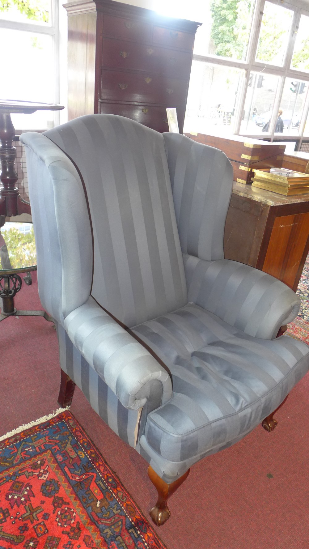 A reproduction Georgian style wing back chair with claw and ball front feet and upholstered in blue