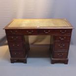 A 19th Century mahogany kneehole desk with leather top over an arrangement of eight drawers raised