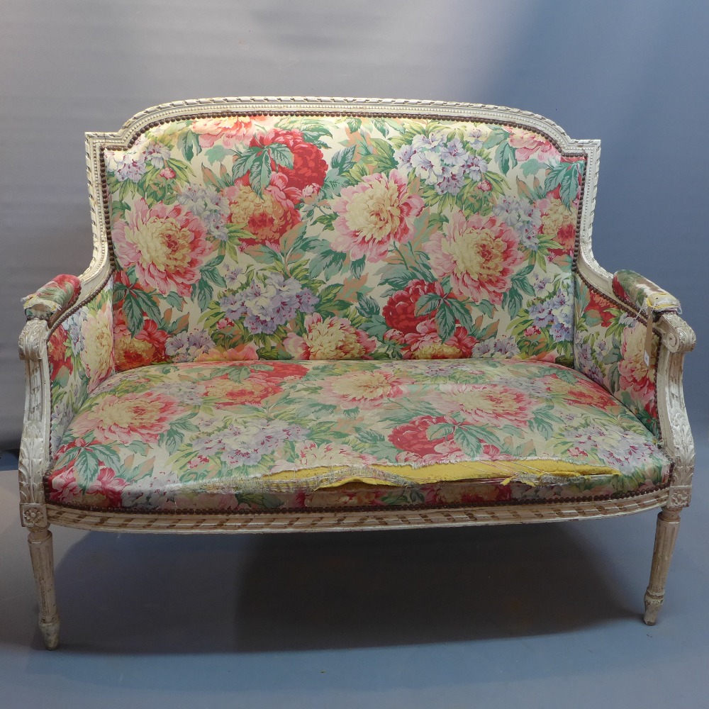 An early 20th Century French white painted settee with carved arm rests,