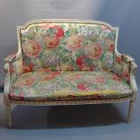 An early 20th Century French white painted settee with carved arm rests,