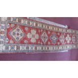 A red ground Kazak runner, geometric designed medallions to centre,