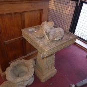 A reconstituted stone bird bath together with two stone shoe planter and a stone otter