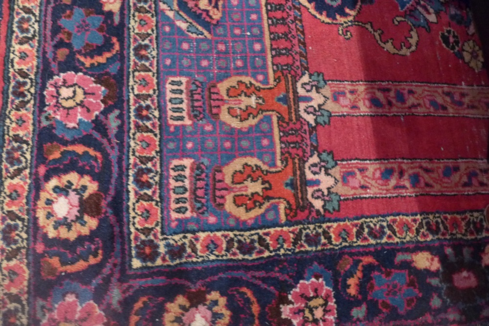 A North West Persian rug decorated with a vase of flowers in a pavilion on a red and blue ground,