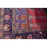 A North West Persian rug decorated with a vase of flowers in a pavilion on a red and blue ground,