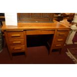 An early 20th Century oak desk having two brush slides over an arrangement of seven drawers,