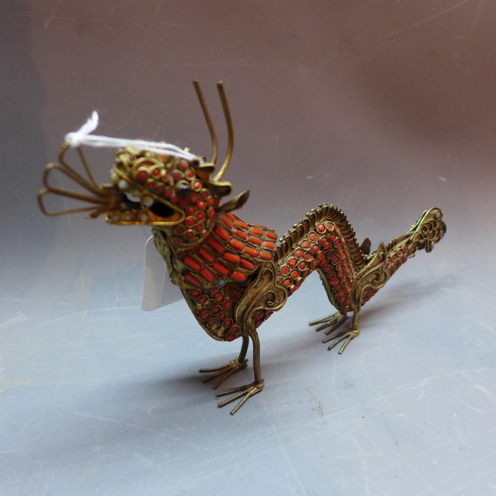 A Chinese brass model of a dragon decorated with coral and turquoise beads.