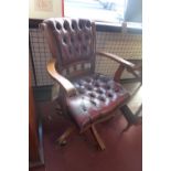 A 20th Century captains swivel chair with red leather button back upholstery.