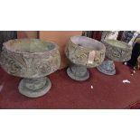 A set of three reconstituted stone urns with floral carving.