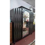 A 1930's ebonised French Gothic triple armoire the central mirrored door with bevelled plate