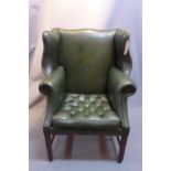 A late 19th Century/early 20th Century green leather wing back arm chair.