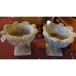 A pair of reconstituted stone urns with floral carving