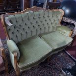 A Louis XV style walnut two seater settee having floral carving and green velour upholstery.