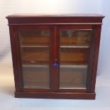 A mahogany floor standing bookcase with glass doors.