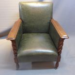 An Edwardian oak club arm chair with green leather upholstery and barley twist supports.