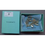 A silver ladies Tiffany bracelet having five attached handbag charms with original box and pouch.