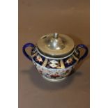 A TWIN HANDLED IMARI STYLE SUGAR BOWL WITH HALLMARKED SILVER RIM + LID