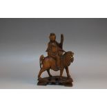 A CHINESE HARDWOOD CARVING OF GUANYIN RIDING A LION, H 21.5 cm