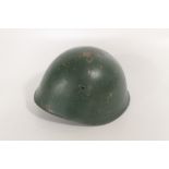 AN ITALIAN STEEL COMBAT HELMET, GREEN PAINTED SHELL, WITH ORIGINAL LEATHER LINER AND CHIN STRAP. Th