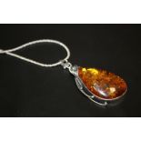 A LADIES SILVER NECKLACE WITH A LARGE AMBER PENDANT