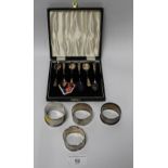 A SELECTION OF FOUR ASSORTED SILVER NAPKIN RINGS, TOGETHER WITH A CASED SET OF SOUVENIR SPOONS