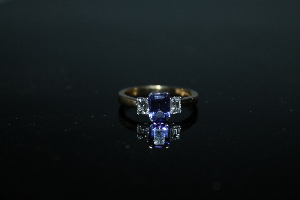 A HALLMARKED 18 CARAT GOLD TANZANITE AND DIAMOND RING, set with a central emerald cut tanzanite of