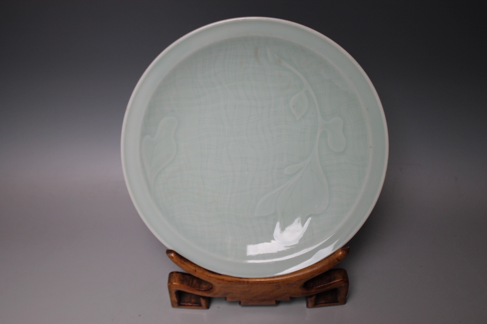 A CHINESE CELADON DISH ON A HARDWOOD DISPLAY STAND, Dia 25 cm