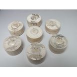 A COLLECTION OF SEVEN 19TH CENTURY ANGLO INDIAN CARVED IVORY LIDDED TRINKET POTS, of circular form,